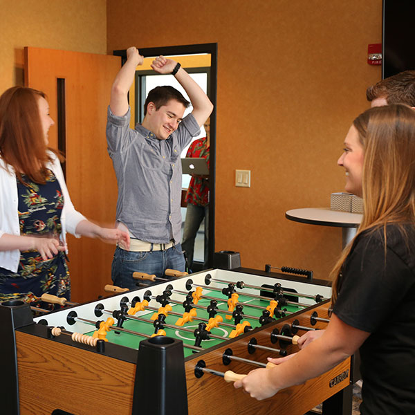 Teammates playing foosball and smiling