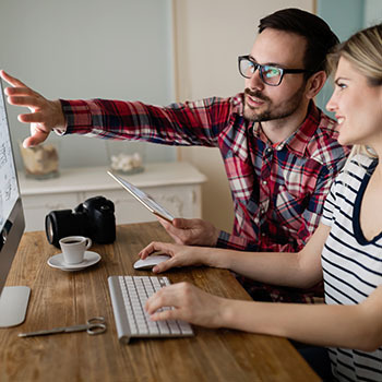 Photo of 2 individuals performing a user experience analysis pointing at a computer screen