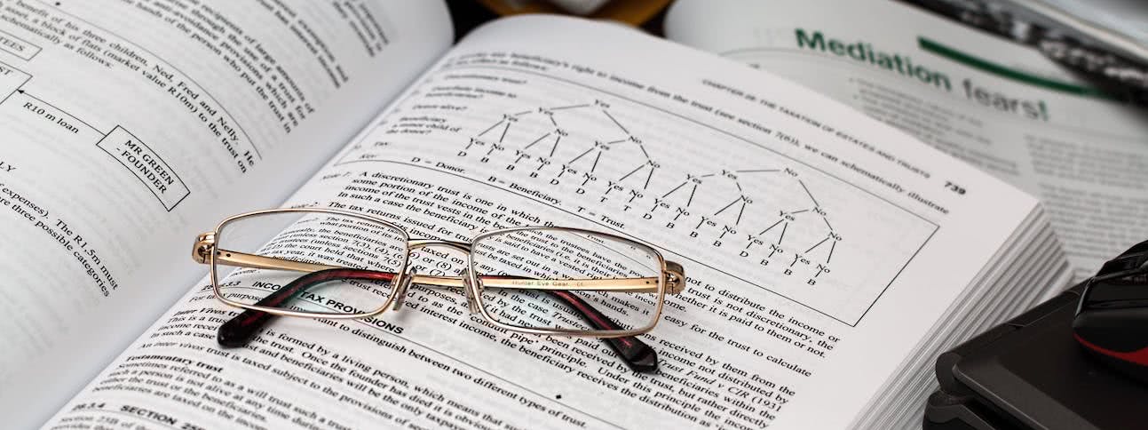 A pair of glasses sitting on an open book showing a decision tree
