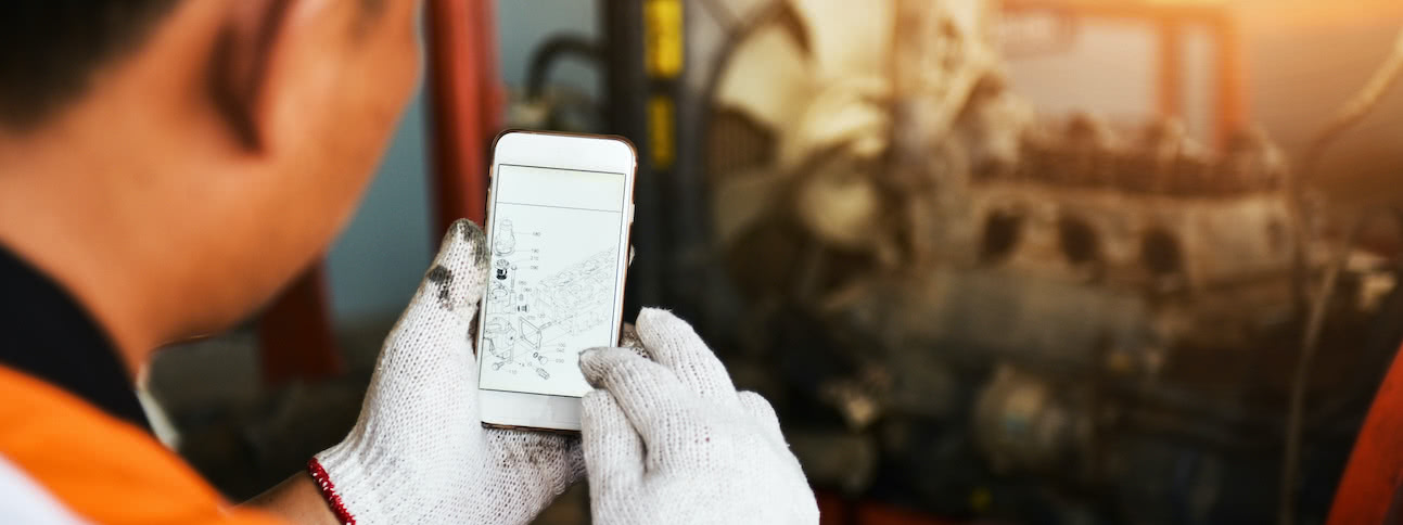 industrial worker looking at schematic plans on his phone in a factory setting