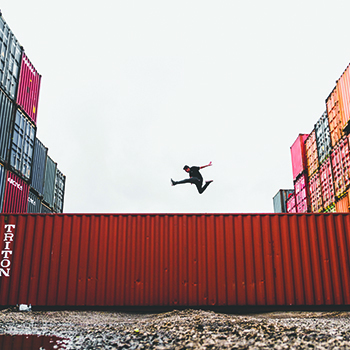 man jumping over shipping container