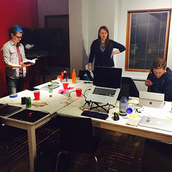 Teammates having discussion around desk with laptops