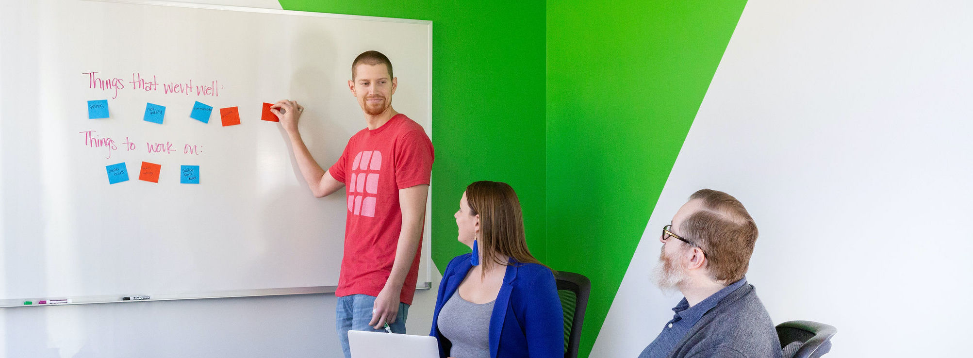An Agile team putting sticky notes on a whiteboard during a retrospective
